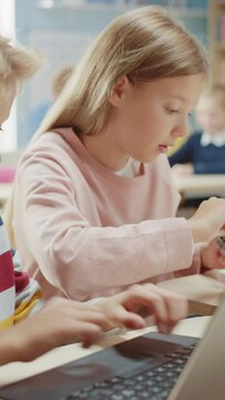 Elementary School Robotics Classroom: Portrait of Girl and Boy Talking while using Computer, Assembling Robot, Programming Software, Coding. Video Footage with Vertical Screen Orientation 9:16