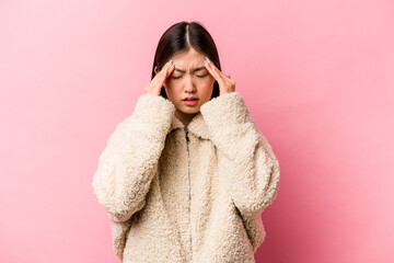 Young Chinese woman isolated on pink background having a head ache, touching front of the face.