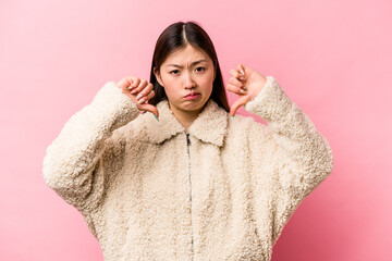 Young Chinese woman isolated on pink background showing a dislike gesture, thumbs down. Disagreement concept.