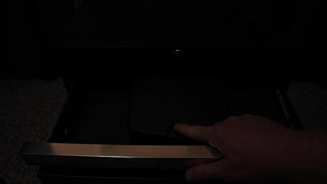 Man uses his fingerprint to open a biometric safe and pick up a handgun as police lights flash