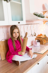 Girl in the kitchen with a rolling pin for rolling dough