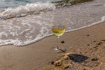 Romantic glass of white wine, on the sea beach. Wine tasting and relaxation at the resort