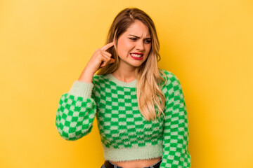 Fototapeta premium Young caucasian woman isolated on yellow background covering ears with hands.