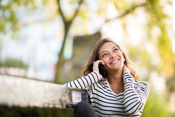 happy young woman talking on cellphone in park