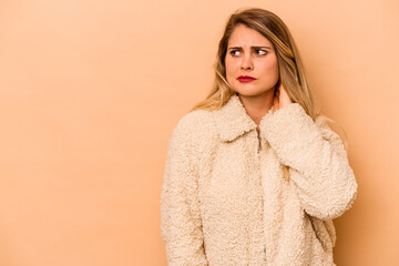 Young caucasian woman isolated on beige background touching back of head, thinking and making a choice.