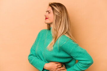 Fototapeta premium Young caucasian woman isolated on beige background suffering a back pain.