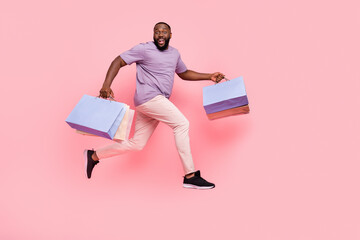 Full length body size view of attractive cheery guy jumping delivering gifts isolated over pink...