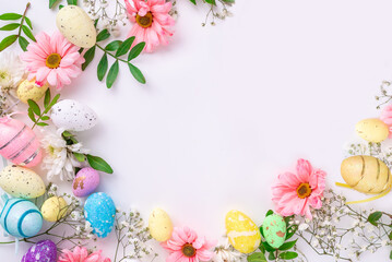Spring Easter background with multicolored eggs and spring flowers. Top view flat lay background . Greeting card pattern with copy space.