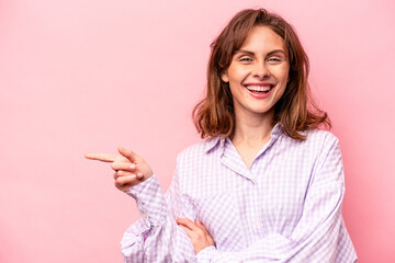 Young caucasian woman isolated on pink background smiling cheerfully pointing with forefinger away.