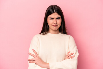 Young caucasian woman isolated on pink background frowning face in displeasure, keeps arms folded.