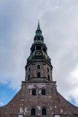 Obraz premium The tower of St. Peter's Church against blue sky with clouds in the Old Town Riga, Latvia
