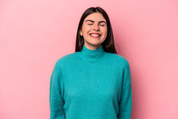 Young caucasian woman isolated on pink background laughs and closes eyes, feels relaxed and happy.