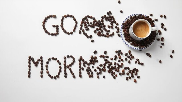 Coffee beans spelling the word "good morning" and a cup of coffee. Stop motion.