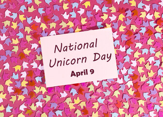 Festive background with multi-colored confetti in the form of unicorns. Concept for National Unicorn Day. Cardboard sign with the inscription.