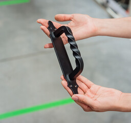 Wrought-iron door handle in the hands of a girl. Separate metal black handle