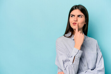 Young caucasian woman isolated on blue background looking sideways with doubtful and skeptical...