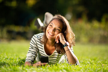 attractive young woman relaxing in park with cellphone