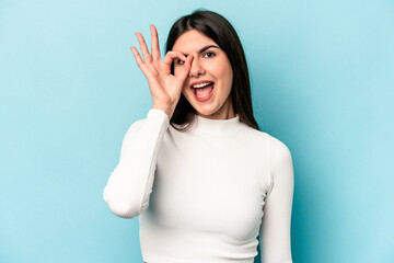 Young caucasian woman isolated on blue background excited keeping ok gesture on eye.