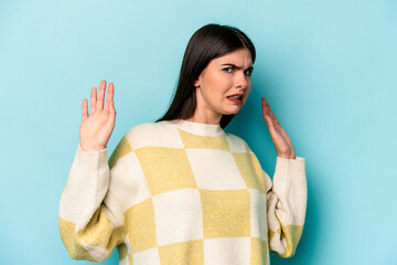 Young caucasian woman isolated on blue background being shocked due to an imminent danger