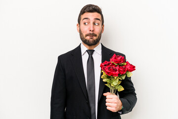 Young caucasian man holding a bouquet of flowers isolated on white background confused, feels doubtful and unsure.