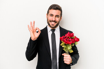 Young caucasian man holding a bouquet of flowers isolated on white background cheerful and confident showing ok gesture.