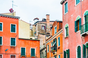 Fototapeta na wymiar Colorful architecture in Venice, Italy. Red facades of the houses and windows with green shutters