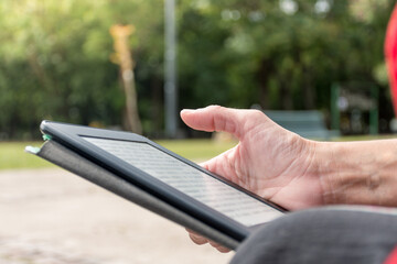 Woman's hand reading an electronic book outdoors with copy space.
