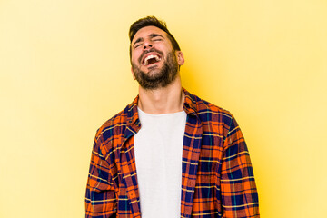 Young caucasian man isolated on yellow background relaxed and happy laughing, neck stretched showing teeth.