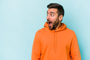 Young caucasian man isolated on blue background being shocked because of something she has seen.