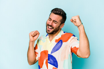 Fototapeta premium Young caucasian man isolated on blue background celebrating a special day, jumps and raise arms with energy.