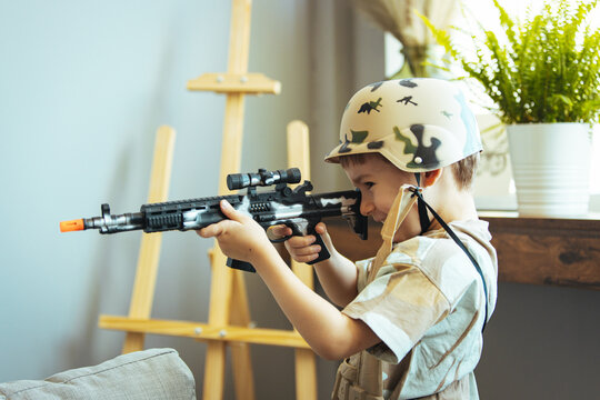Little boy playing soldiers in living room. In his imagination the boy are defending the encircled city of Bastogne aganist the enemy.  Entertainment for kids indoors. Offline games.
