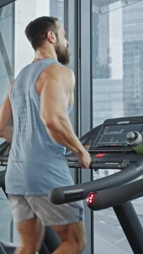 Athletic Muscular Man Running on a Treadmill, Leg and Cardio Day. Strong Man Training in the Modern Gym. Front View of Low Ground Shot. Focus on Legs. Vertical Screen Orientation Video 9:16