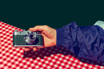 Concept of pop art photography. Using retro gadgets. Human hand holding photo camera isolated on green background. Vintage fashion style. Concept of nostalgia