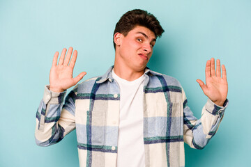 Young caucasian man isolated on blue background being shocked due to an imminent danger