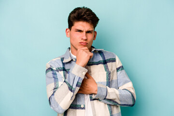 Obraz premium Young caucasian man isolated on blue background thinking and looking up, being reflective, contemplating, having a fantasy.