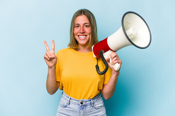 Young caucasian woman holding a megaphone isolated on blue background showing number two with fingers.