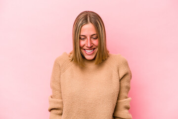 Young caucasian woman isolated on pink background laughs and closes eyes, feels relaxed and happy.