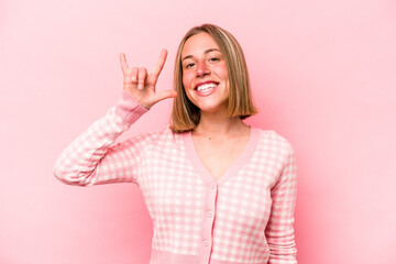 Young caucasian woman isolated on pink background showing a horns gesture as a revolution concept.