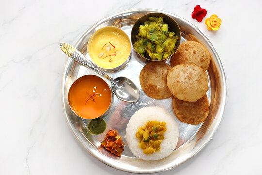 Indian vegetarian Thali or platter includes Aloo ki sabji, dal rice, Puri bhaji, Shrikhand or Srikhand, Aamras, papad, pickle, and chutney. Mashed potato curry or masala. Indian Festival food Thali.