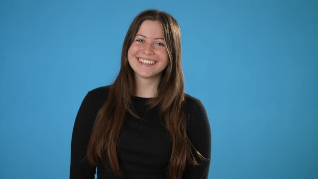 Portrait of happy smiling young brunette woman 20s thumbs up, wears black shirt isolated on plain blue background copy space studio portrait. People emotions lifestyle concept