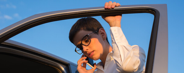 	
Young beautiful woman calling towing service after her car broke on the road on a sunny day - obrazy, fototapety, plakaty