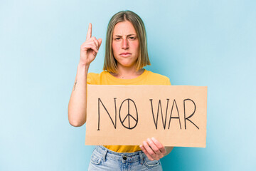 Young caucasian woman holding no war placard isolated on blue background