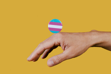 hand and pin button with transgender pride flag