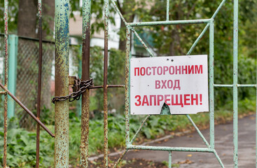 Сlosed gate with inscription "No entry for unauthorised people" on Russian. Restricted area or prohibited zone concept.