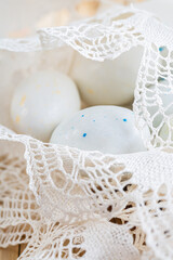 Sweet white eggs with spots in lace and a blurred background. Greeting cards for Easter. Toned image. Shallow depth of field. The artistic intend and the filters.