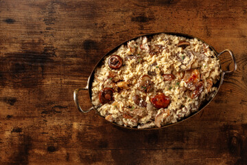 Mushroom risotto, rice with mushrooms and cheese, shot from above on a dark rustic wooden background with a place for text