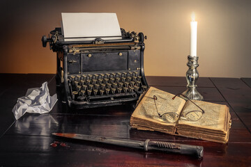Vintage typewriter on a table next to a murdering knife and a book.A detective story concept.