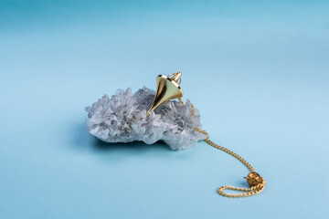 Crystal Sphere and pendulum on blue background  with quartz clusters for recreation and meditation....