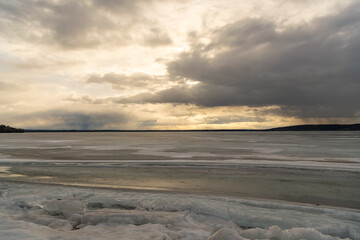 Sunlight breaking through spring clouds over a frozen Lake Dore in back country Ontario..	