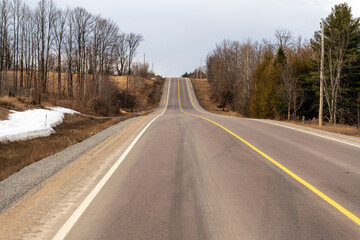 Fototapeta premium A rural roadside as spring arrives, some remnant snow visible. Shot in the farm country of the Ottawa Valley (Ontario, Canada) in early April.